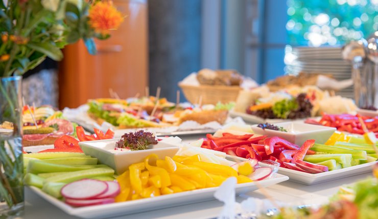 Buffet mit verschiedenen Tellern, auf denen sich frisches Gemüse und anderes Essen befinden.