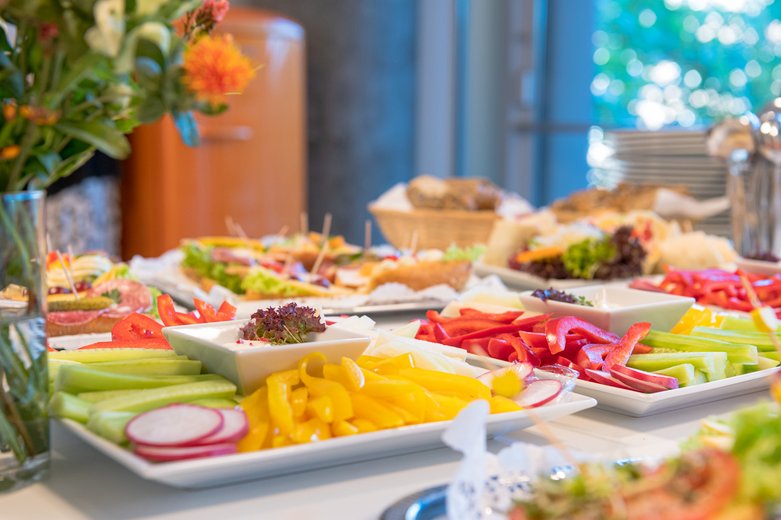 Buffet mit verschiedenen Tellern, auf denen sich frisches Gemüse und anderes Essen befinden.